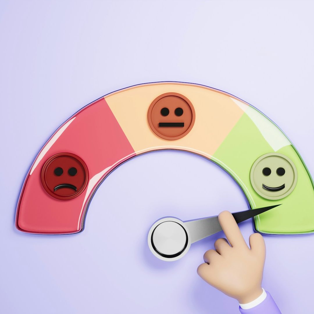 A hand adjusts a smiley face on a feedback meter displaying emotions.